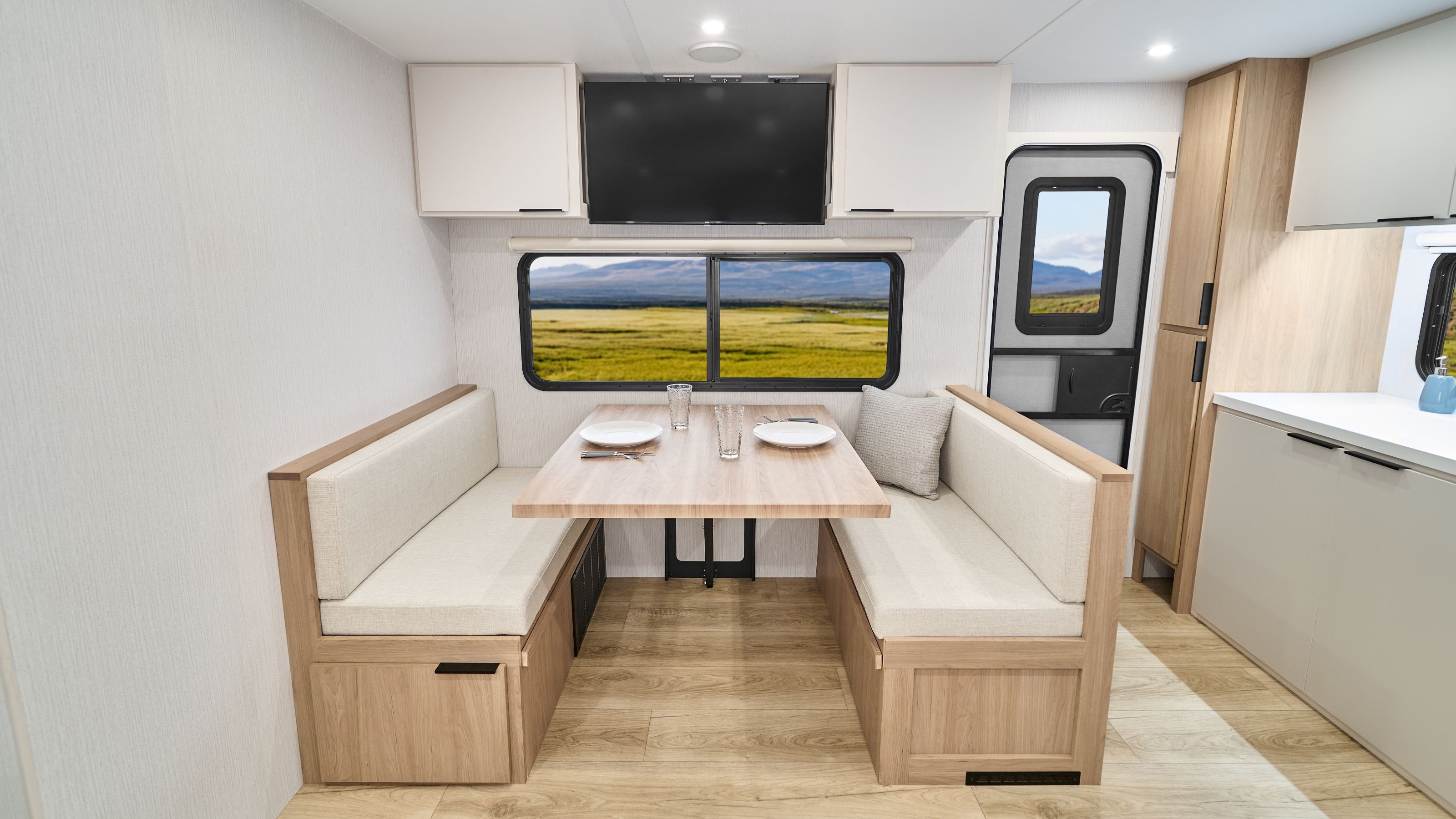 2026 Winnebago Thrive 24RKS — Spacious dinette seating inside the Thrive 24RKS, with storage compartments overhead and under the seating.