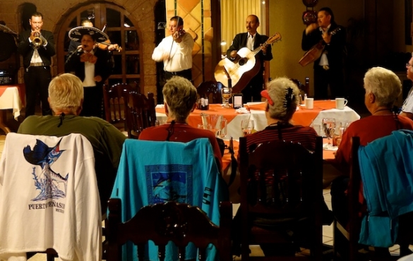 Mariachi band playing at a restaurant and diners listen.