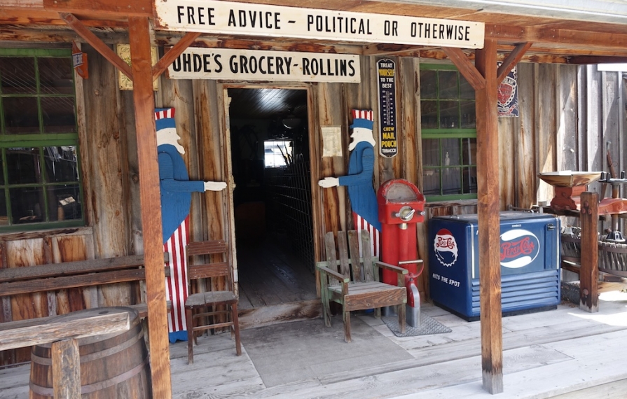 Old wooden store front with sign reading, "Uhde's Grocery - Rollins."