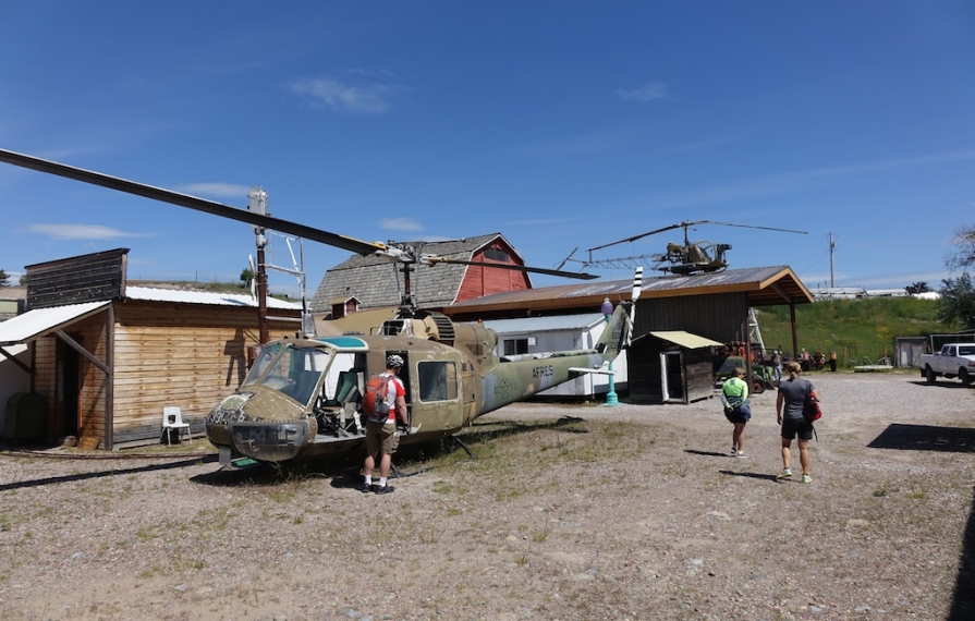 Old helicopter among buildings and tourists at the museum.