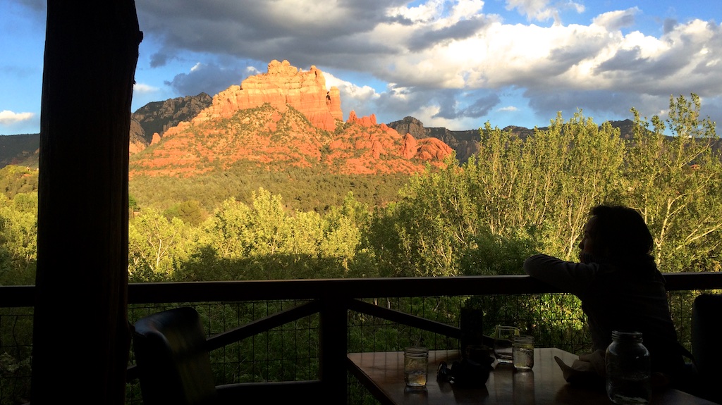 Person sitting at a table looking out over the trees with canyons in view.