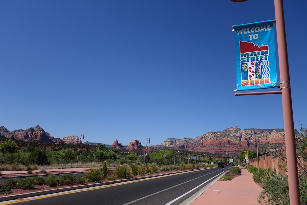 Road past "Welcome to Main Street Sedona" leading to canyons ahead.