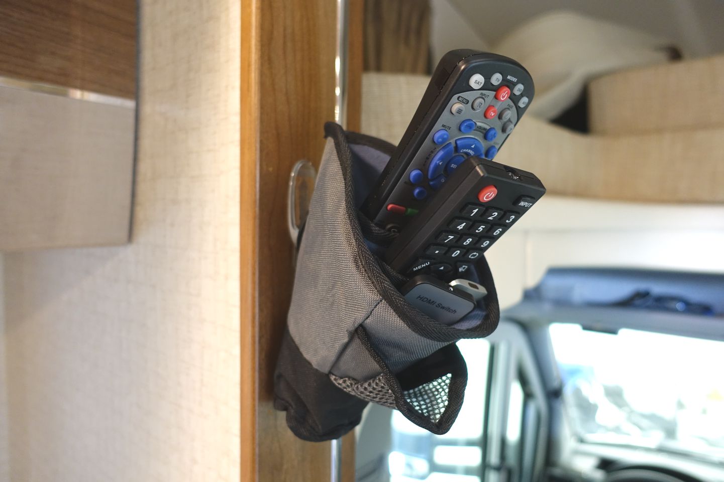 Remotes in a pouch hanging from the wall.