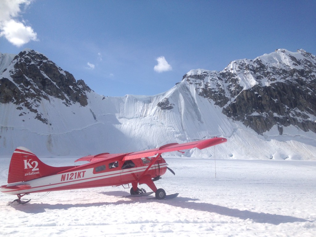 Small red plane landed on a snow covered glacier.