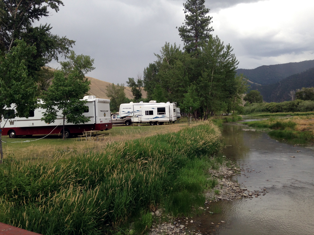 Winnebago Brave and a few other RV's parked in campsites along a river. 