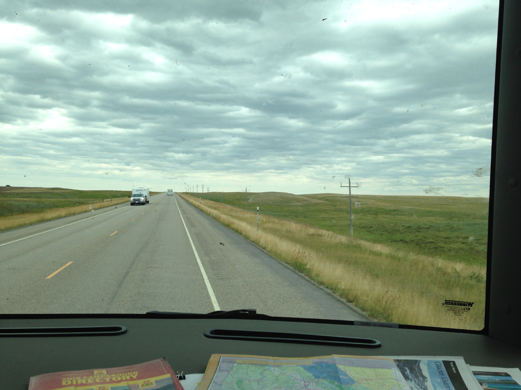 Vehicle traveling along road through open, grassy plain.