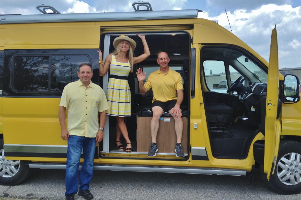 James & Stef standing with Russ Garfin with their new yellow Winnebago Travato.