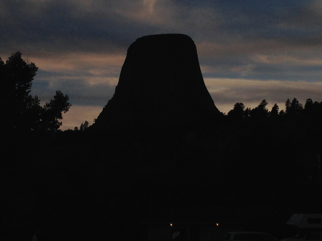 Silhouette of Devils Tower against a darkening sky.
