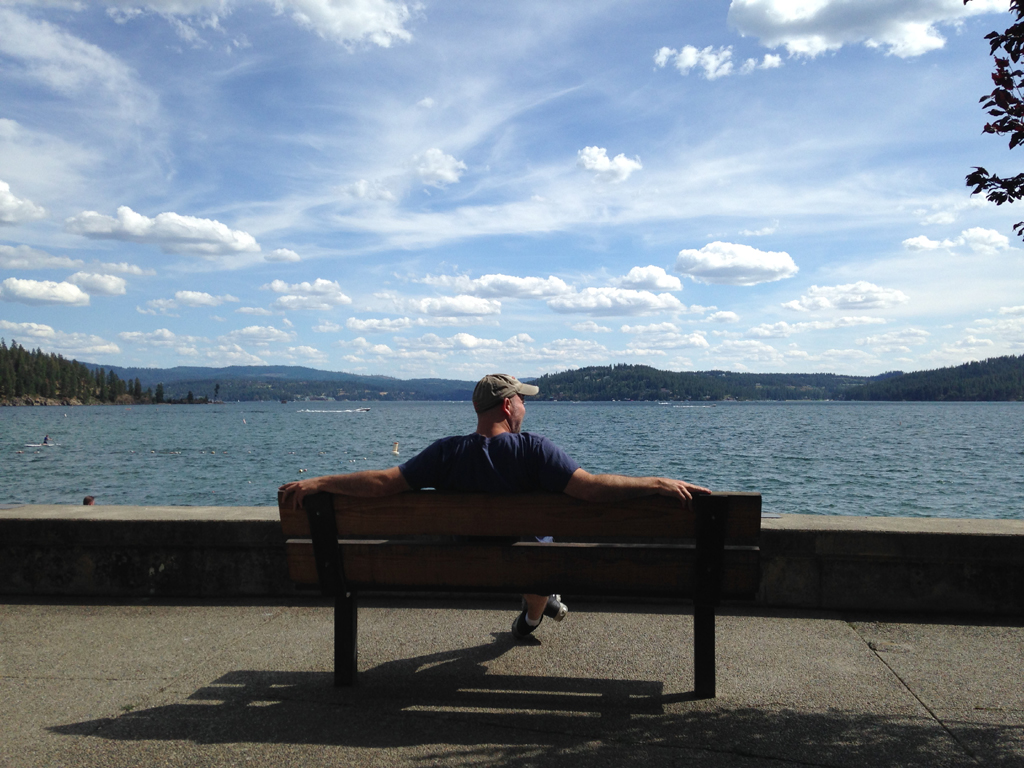 Man sitting on bench overlooking body of water.