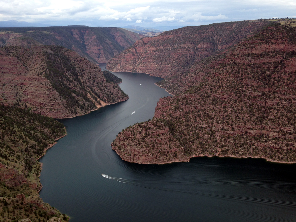 Speedboats driving along the water through a red canyon.