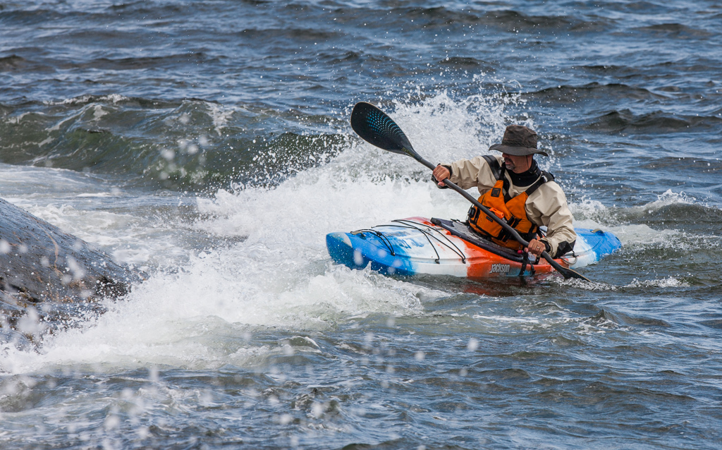 Man in a kayak in what appears to be rougher water.