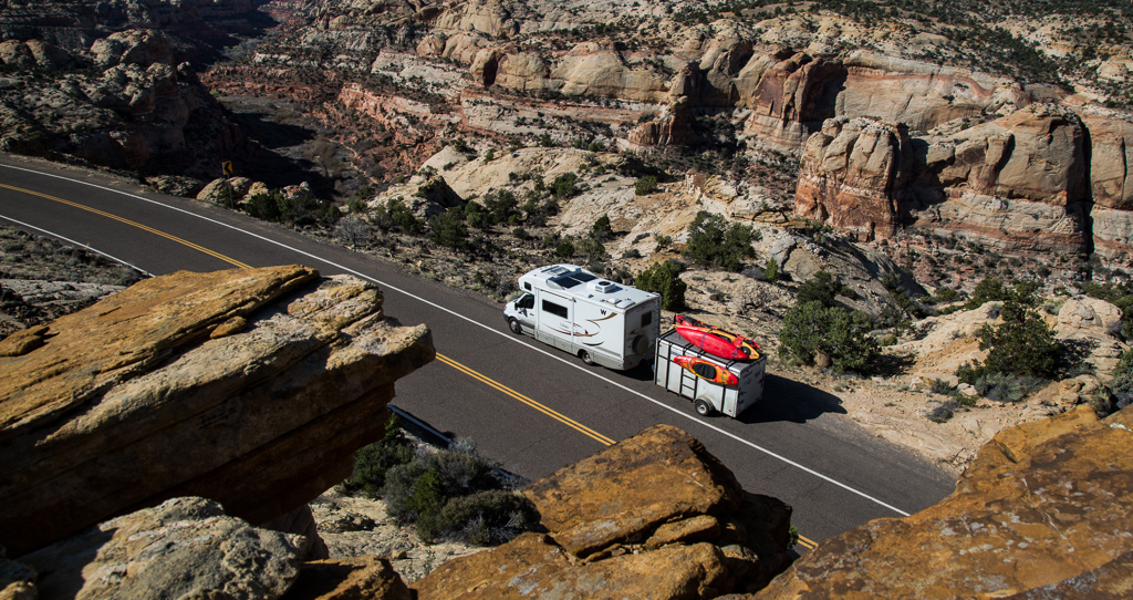 Winnebago View with trailer attached parked on the side of a highway among canyon lands. 
