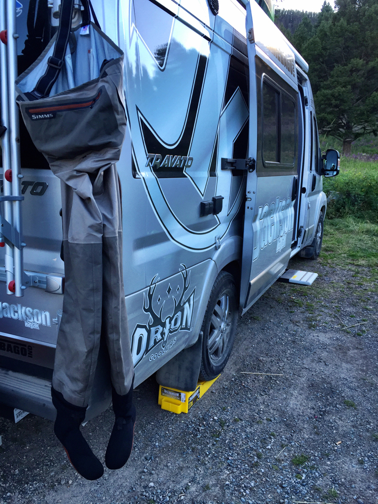 Winnebago Travato parked with Simms fishing waders handing from the backend.
