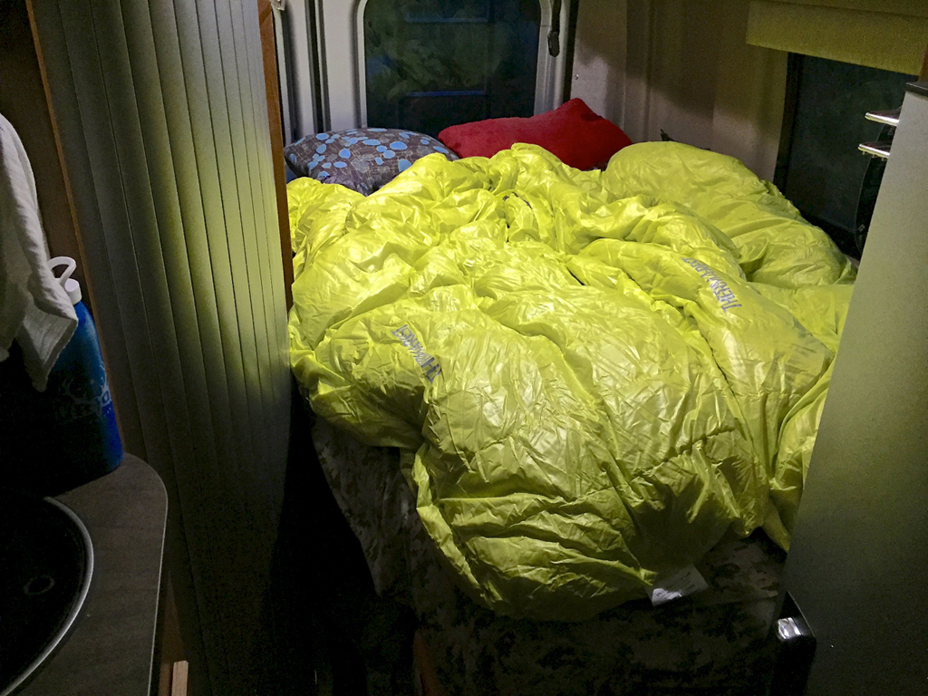 Auriga Therm-a-rest down blanket on bed at the back of the Travato.