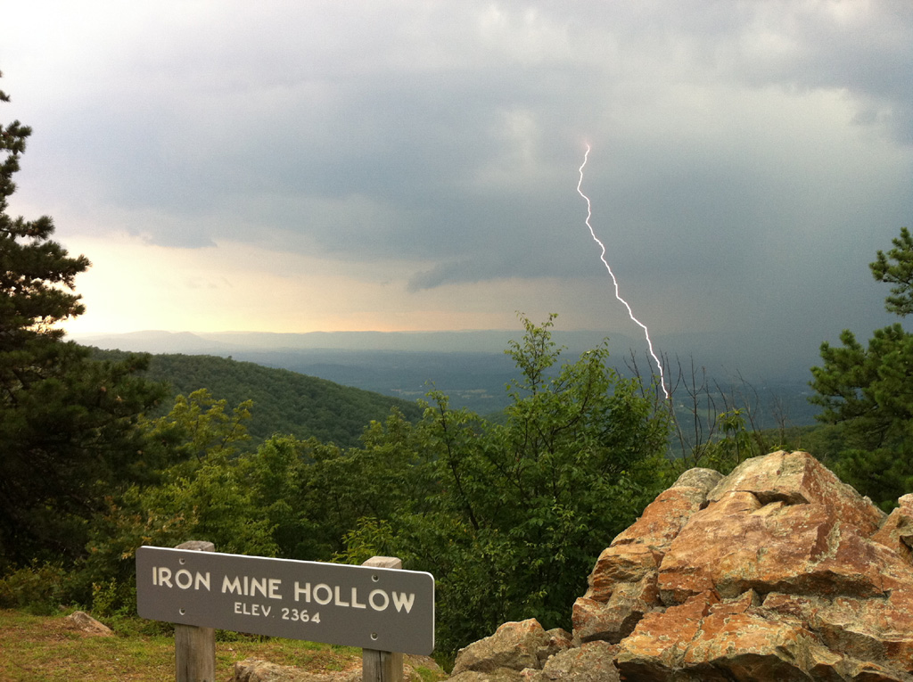 Looking out from Iron Mine Hollow on the Blue Ridge Mountains with a lightning strike going from clouds to the ground.