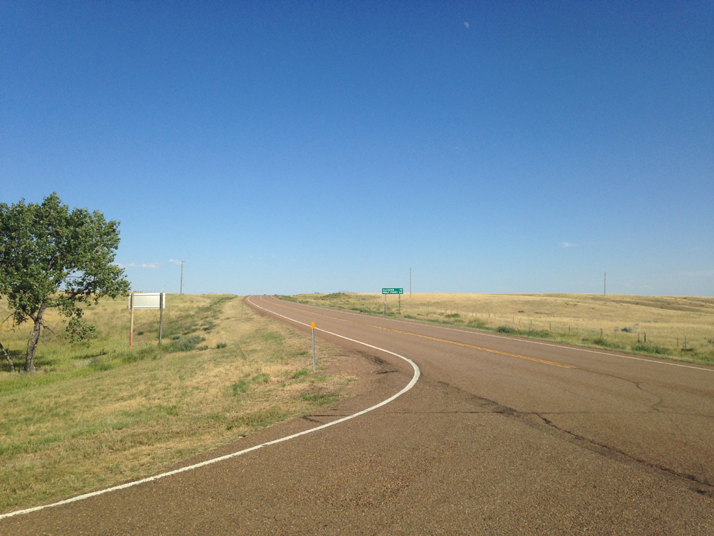 Empty highway with grassy plains on either side.