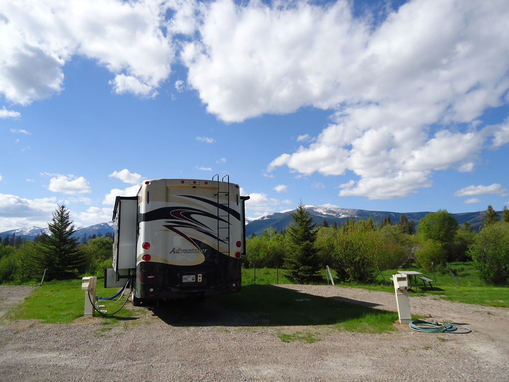 Winnebago Adventurer parked in campsite with a view of the mountains ahead.
