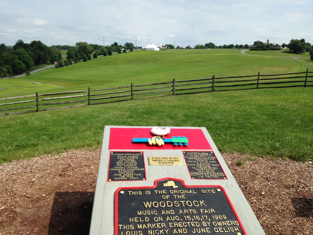 Sign marking the original site of the Woodstock with open field ahead.