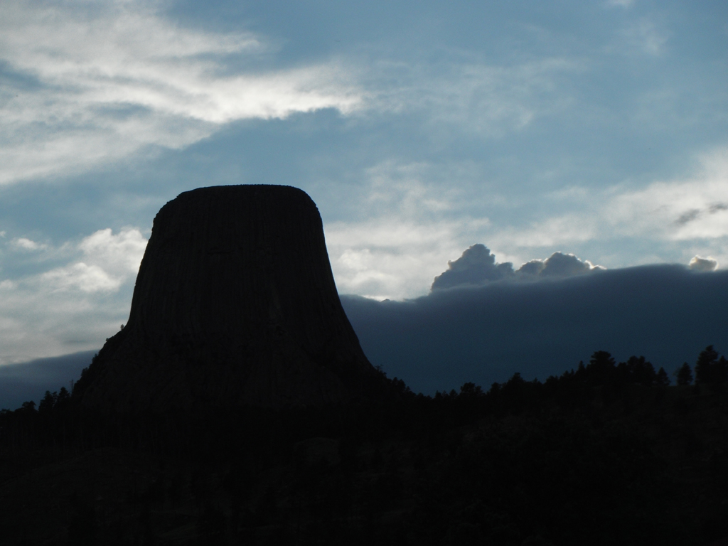 Shillouette of Devil's Tower against cloud covered sky.
