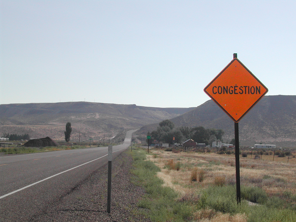 Empty road leading through hills with a sign that reads, "Congestion."