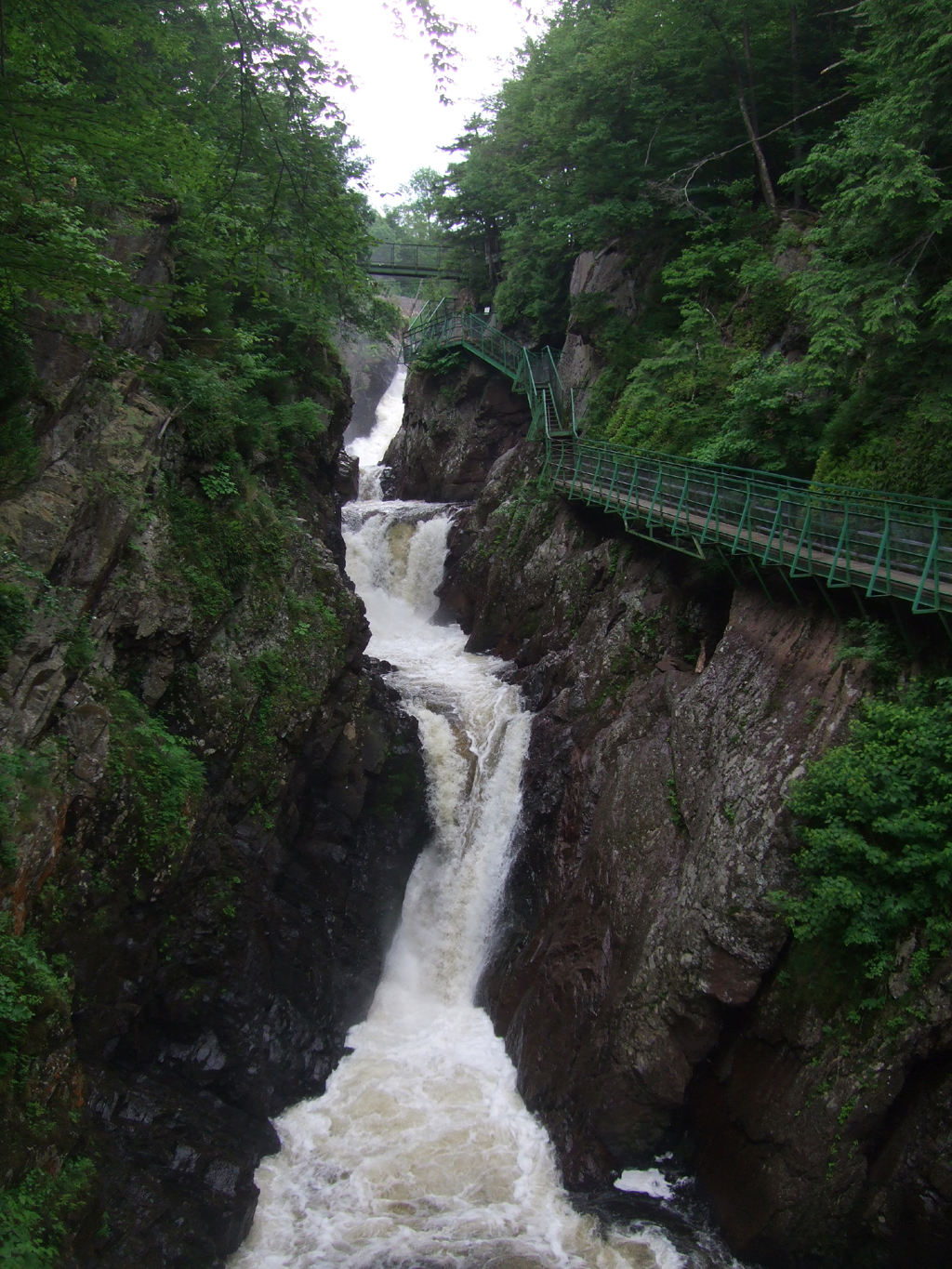 Water cascading through the Flume Gorge. A green walkway scales the side.
