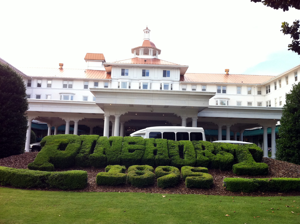 Sculpted bushes that say, "Pinehurst 1895" in front of the big white building.