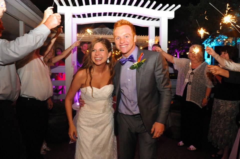 Heath and Alyssa in wedding attire being sent off with sparklers.