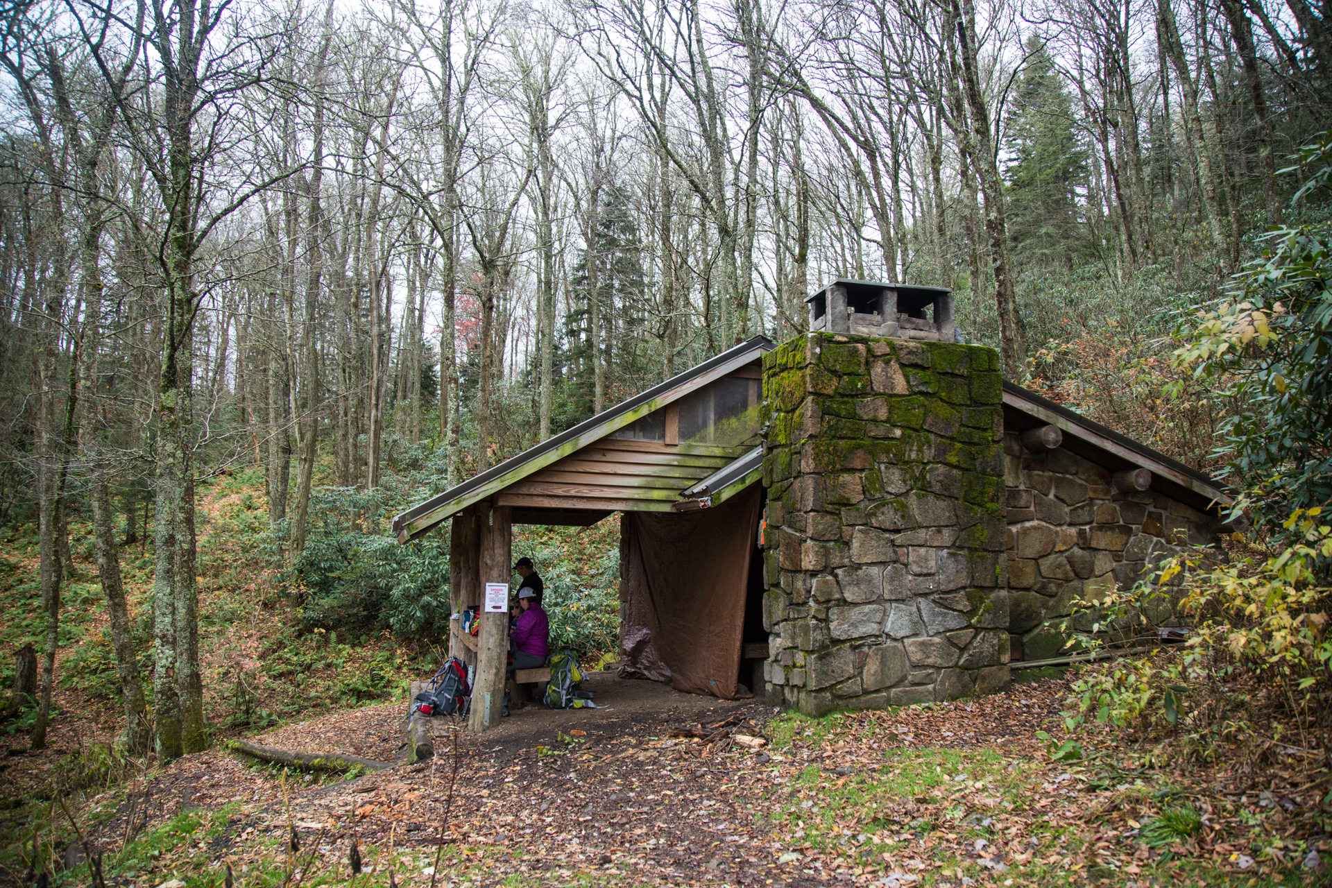 People sitting outside Cosby Knob shelter among the trees.