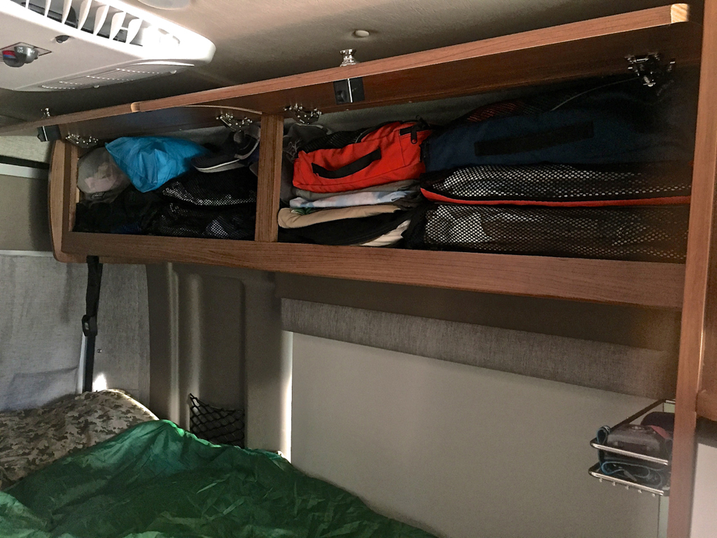 Clothes packed in storage pouches in the upper cabinets.
