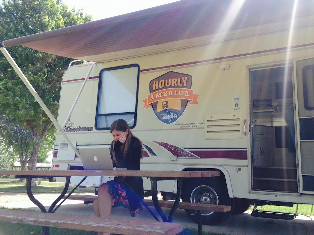 Alyssa working on her laptop while sitting at a picnic table outside motorhome.