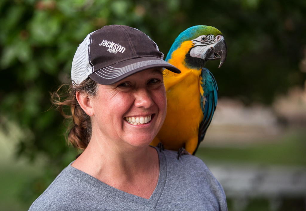 Kathy with a colorful macaw on her shoulder.