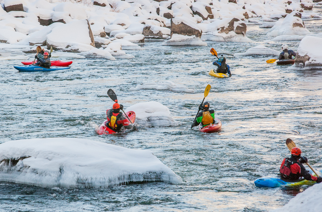 Kayakers avoiding large chunks of ice as they navigate the river.