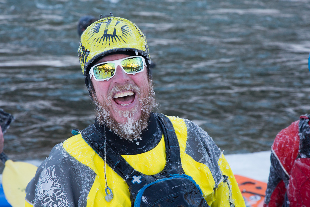 Man with a frozen beard and a big smile on his face next to the river.