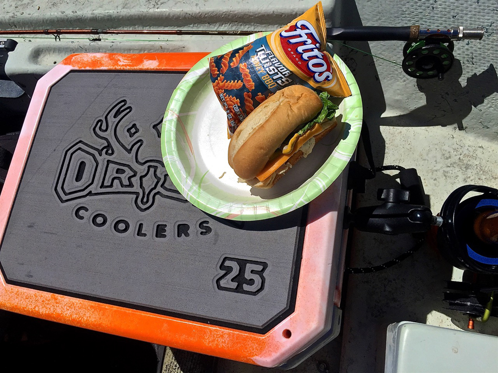 Sandwich and chips sitting on a cooler.