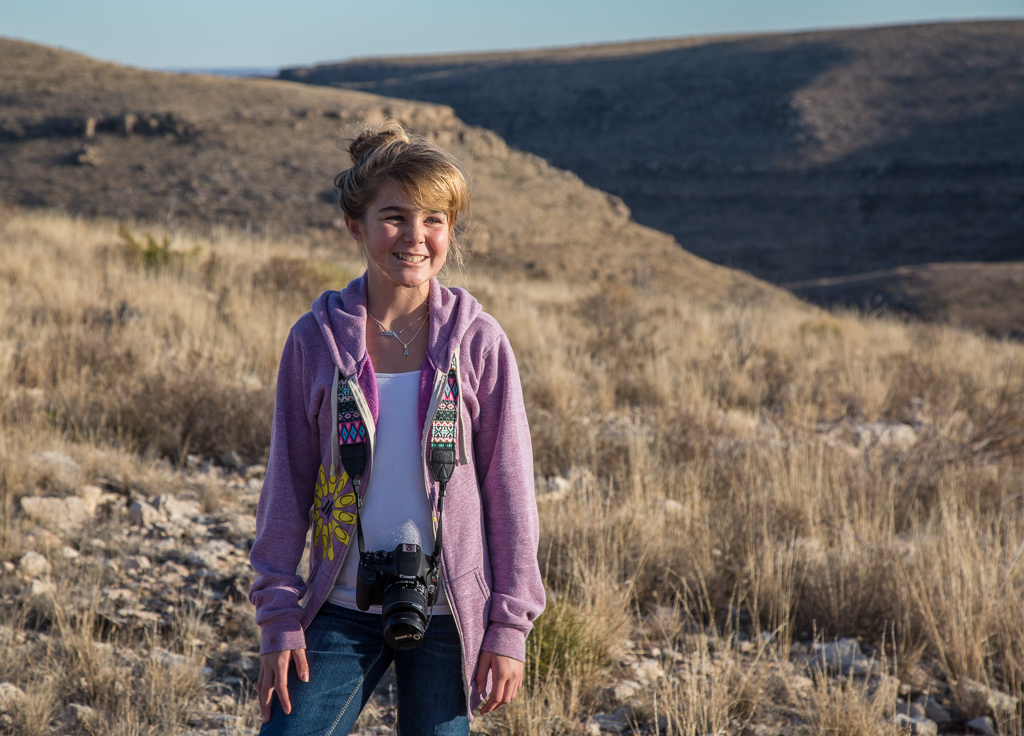 Abby with camera around her next and desert landscape as the background.