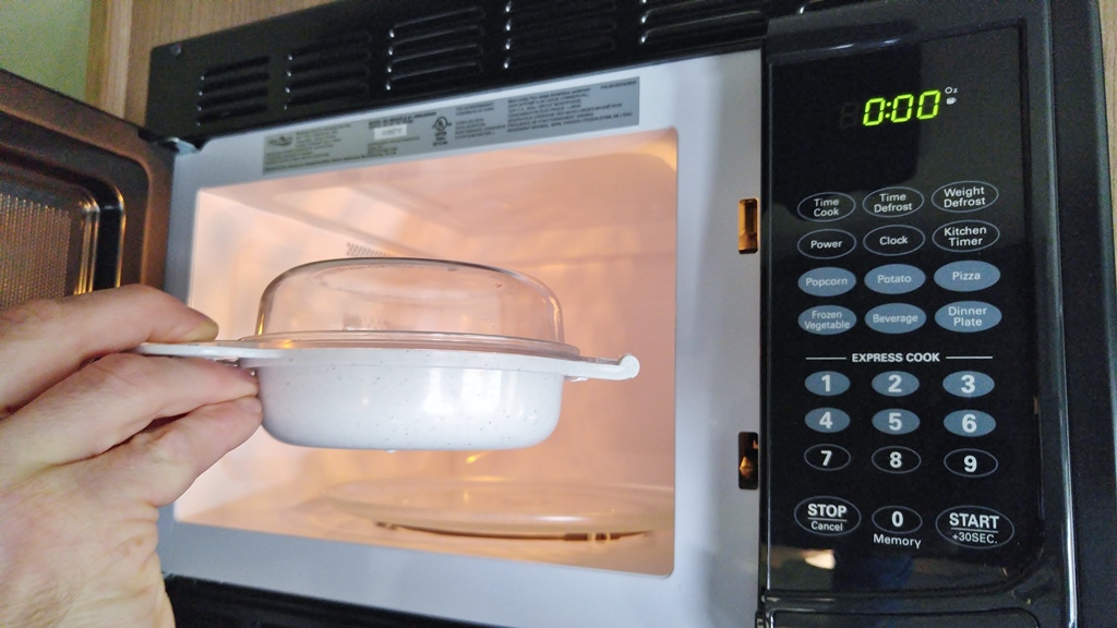 Nordic Ware egg cooker being placed in microwave.
