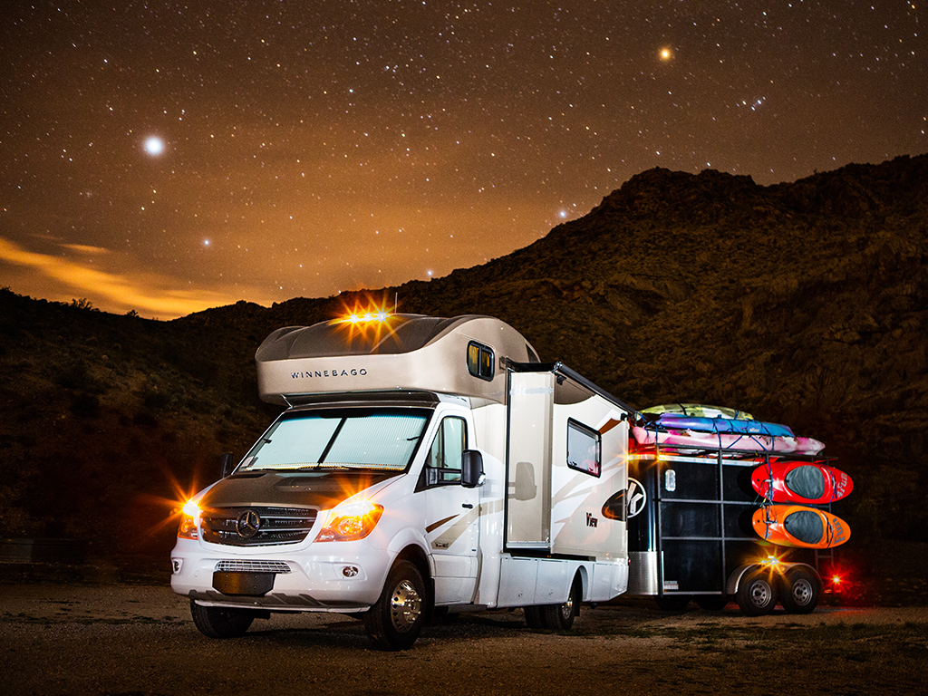 Winnebago View with trailer attached and a star filled night sky overhead.