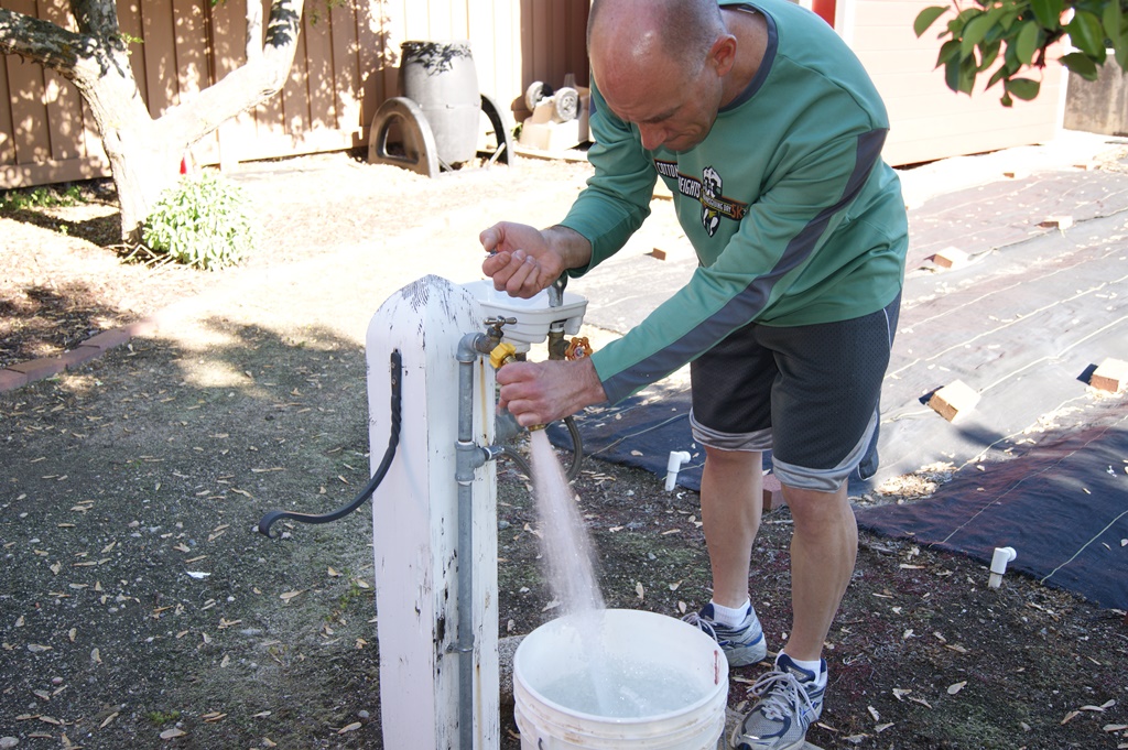 James testing water pressure as it sprays into a bucket.
