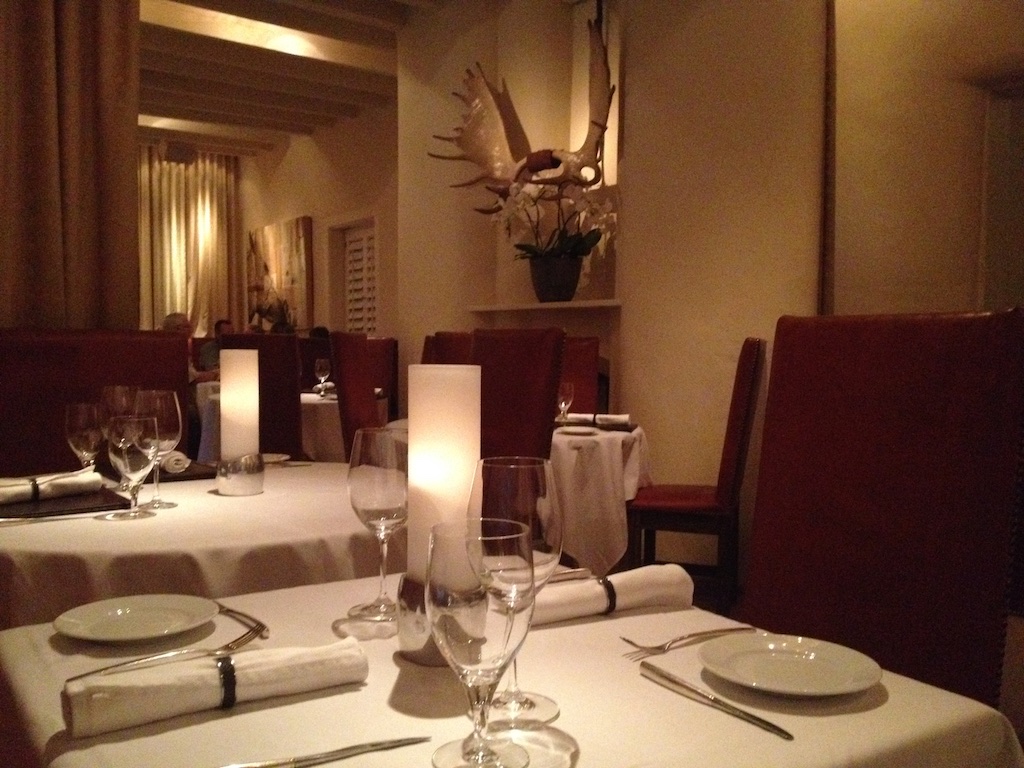Skirted tables with candles lit in fancy restaurant.