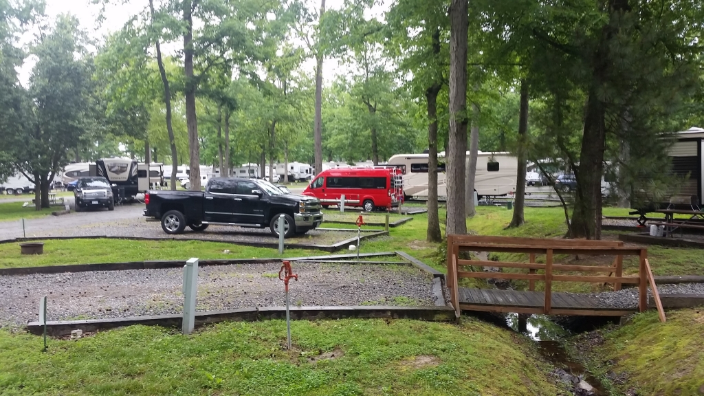 Red Winnebago Travato among other RVs at a campground.