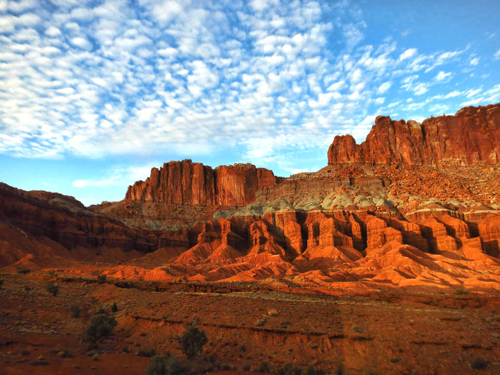 Red canyon landscape with unique clouds in the sky overhead.