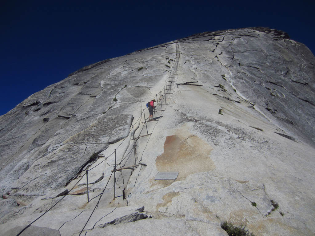 Hiker working their way up the cable line trail to the top of Half Dome.