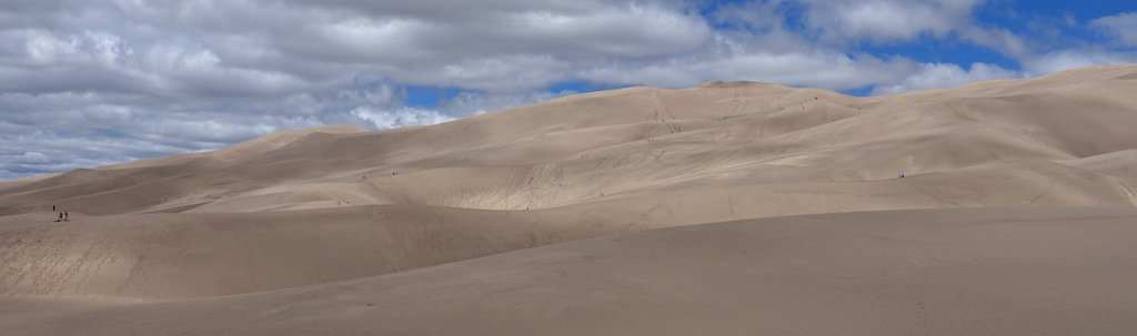 People barely visible among the massive sand dunes.