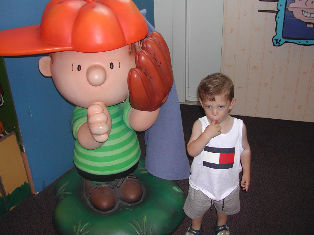 Little boy next to statue of Peanuts character.