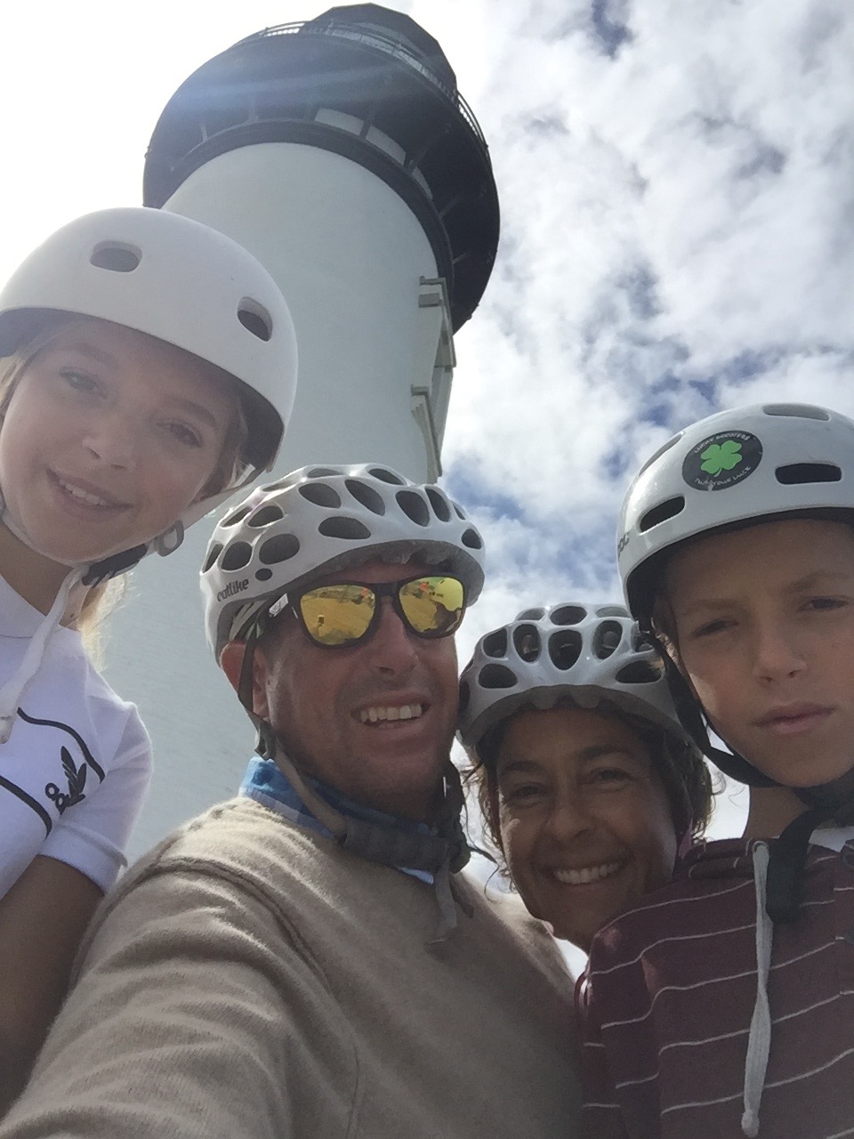 Family selfie with lighthouse behind them.