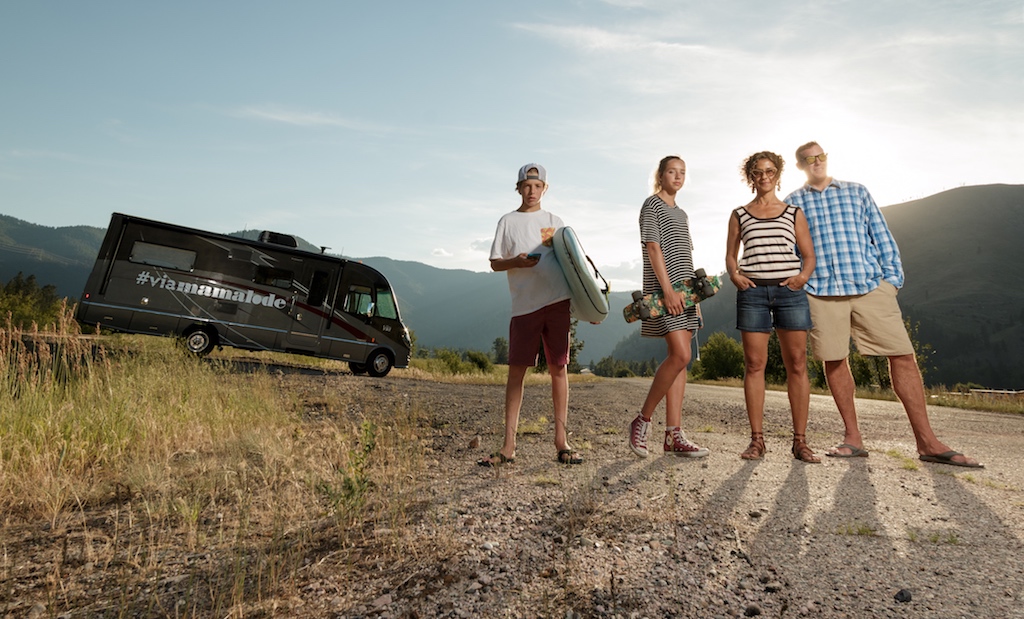 Family standing outside their Winnebago Via with mountains in the background.