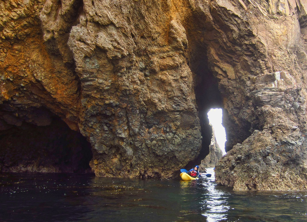 Kayaker making their way through the Caverns of the cliffside.