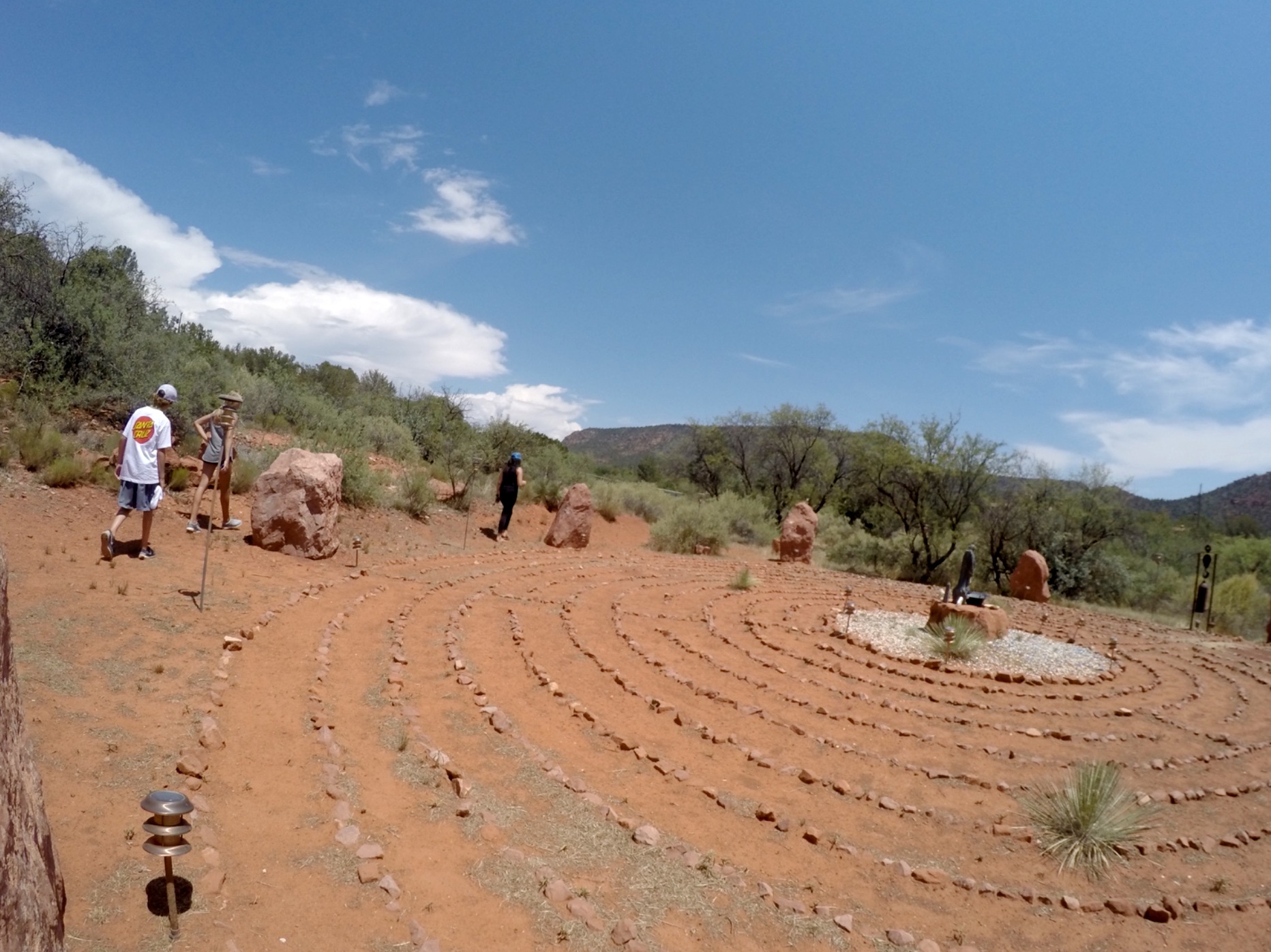 People walking a backyard labyrinth in desert landscape.