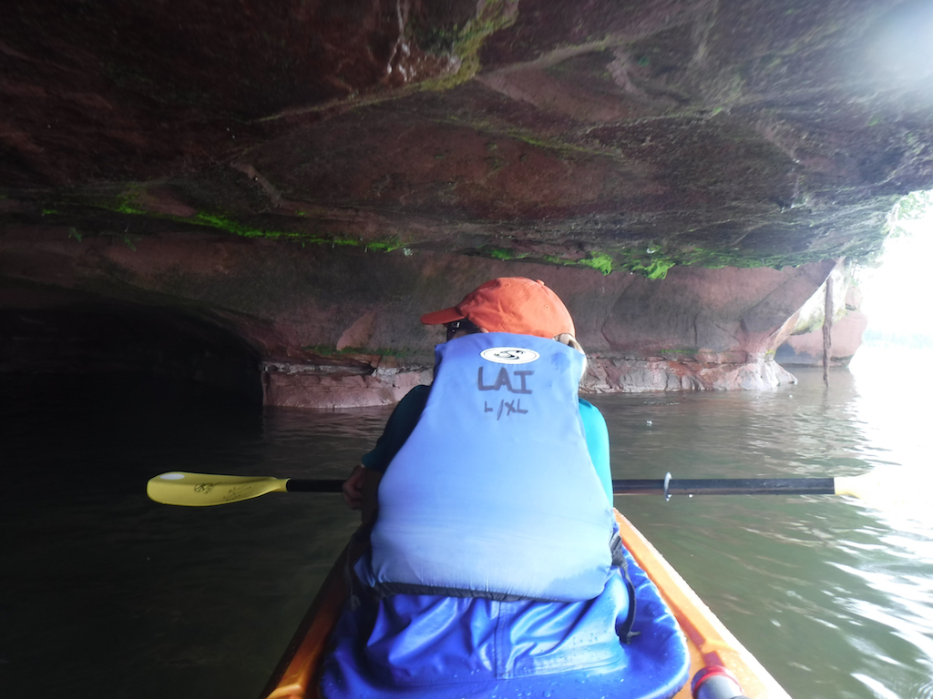 Kayakers under a cave top on Lake Superior.