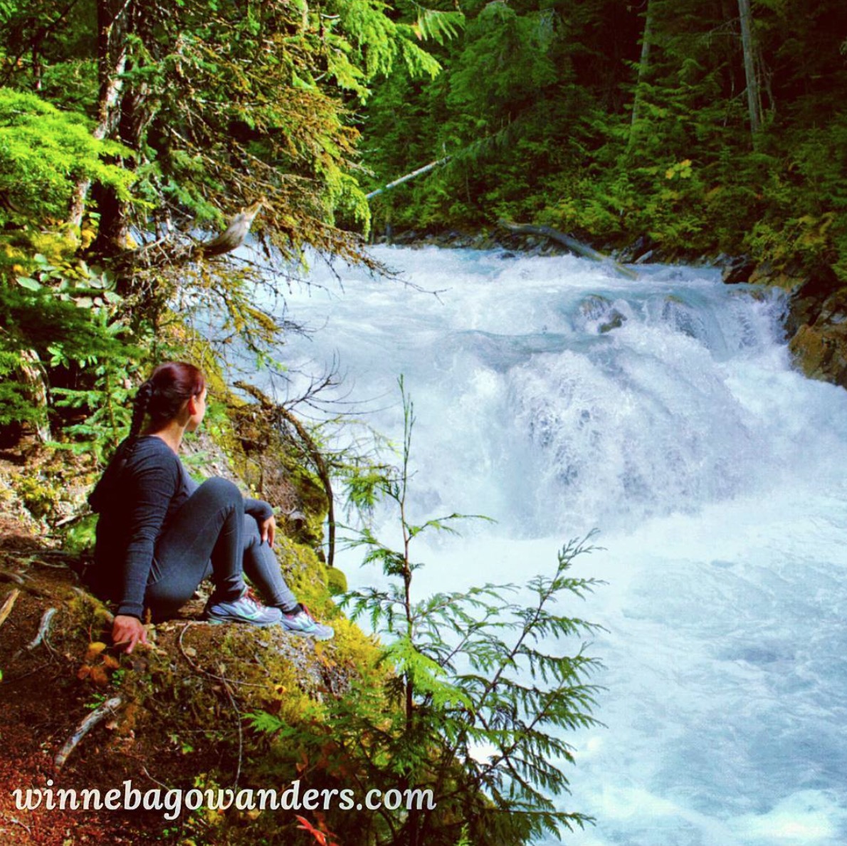 Woman sitting looking out over a waterfall.